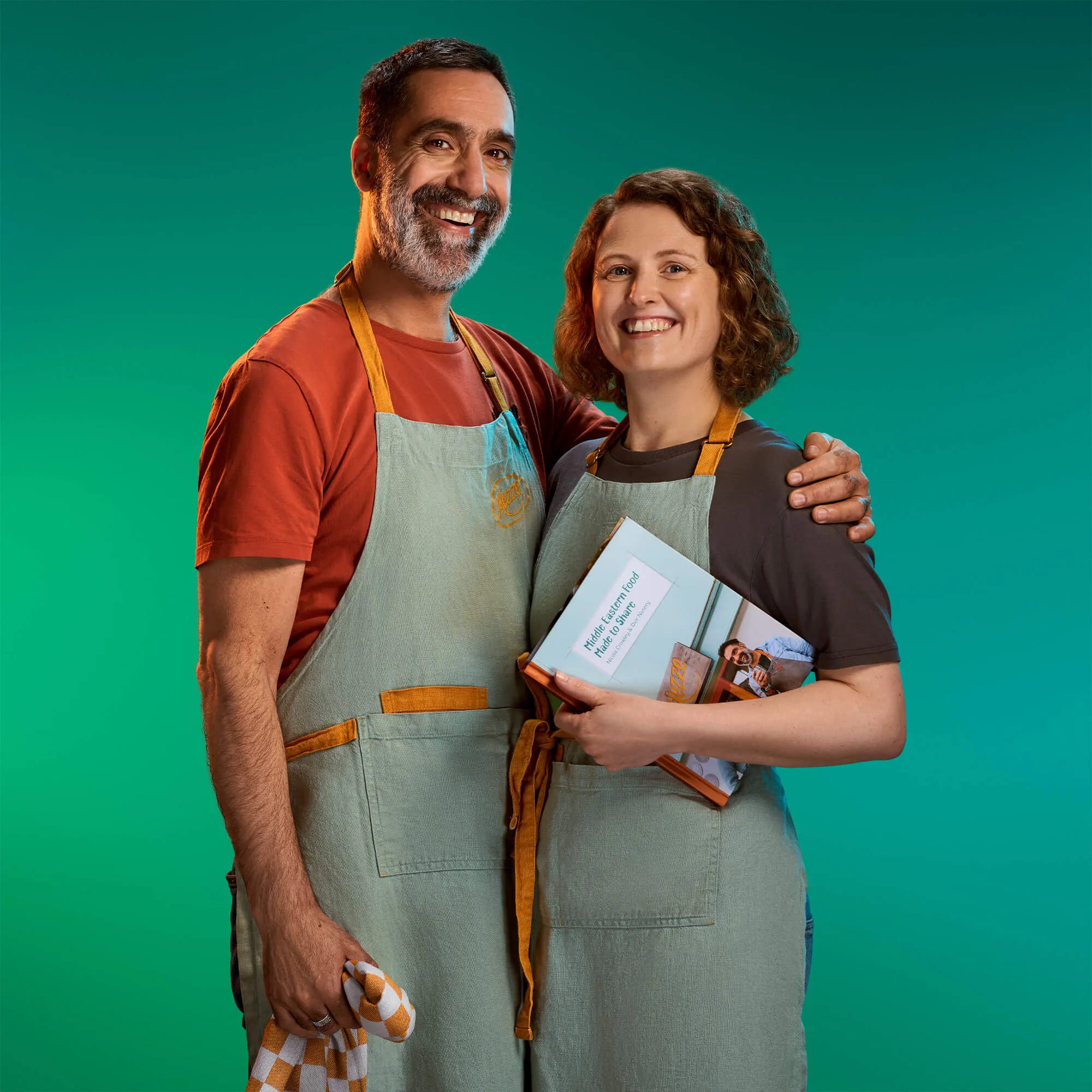 An image of a man and a woman smiling on a green background. Both of them are wearing aprons | FBD Insurance